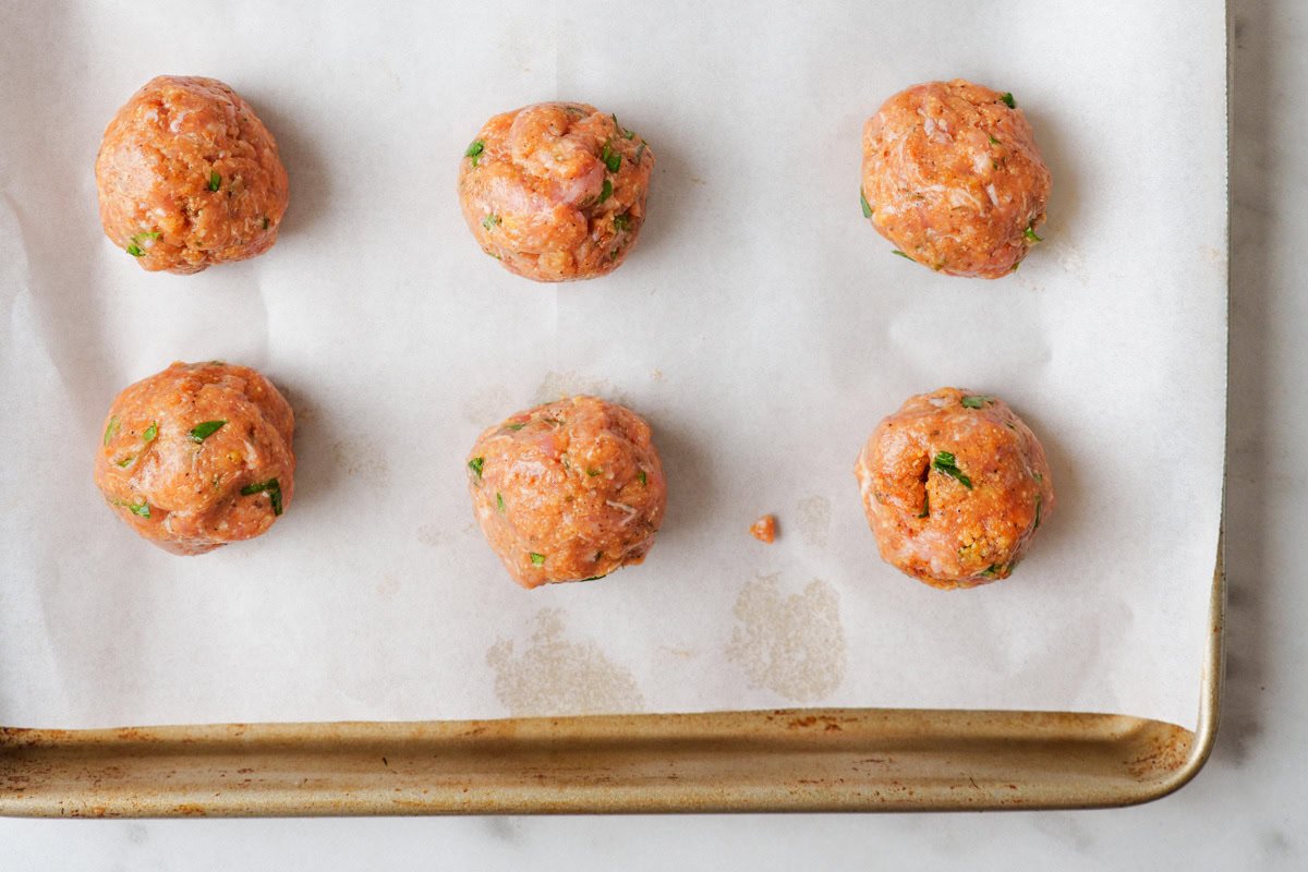 des boulettes de dinde crues disposées sur un papier cuisson