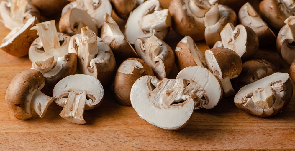 des champignons baby bella coupés en deux sur une planche à decouper