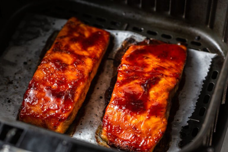 deux morceaux de samon teriyaki cuits placés dans un tiroir d'air fryer