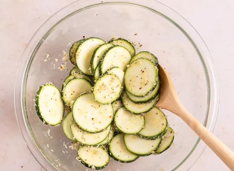 des rondelles de courgette, une cuillere en bois dans un saladier