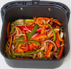 des lanières de poivron et de l'ognon rouge dans le panier d'un air fryer